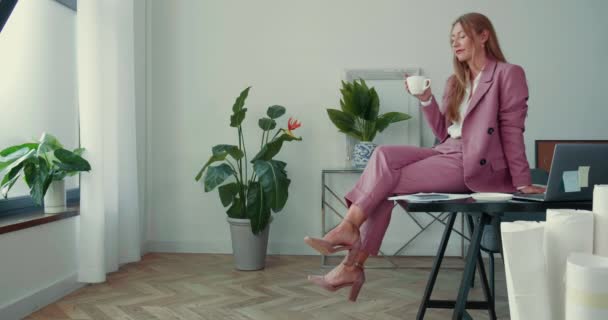 Pause von der Arbeit. Glücklich schöne stilvolle Geschäftsfrau beim Kaffee mit dem Smartphone am hellen Bürotisch. — Stockvideo