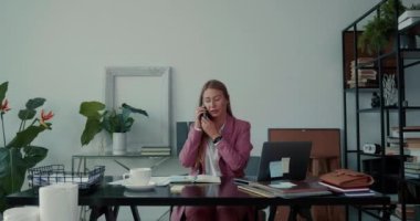 Güzel, ciddi, genç patron iş kadını dizüstü bilgisayarla çalışıyor ve ofis masasında evrak işleriyle meşgul..