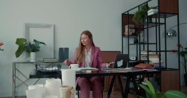 Coopération au travail. Deux belles jeunes femmes d'affaires sérieuses travaillent ensemble avec un ordinateur portable, occupées à la table de bureau moderne. — Video