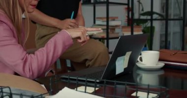 İşbirliği konsepti. Modern ofis masasında laptopla gülümseyen iki güzel ve meşgul genç iş kadını..