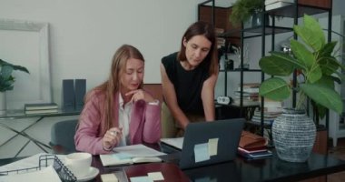 Yardım ve yardım. Modern ofis masasında dizüstü bilgisayar kullanan genç ve güzel bir patron kadın yönetici çalışana yardım ediyor..