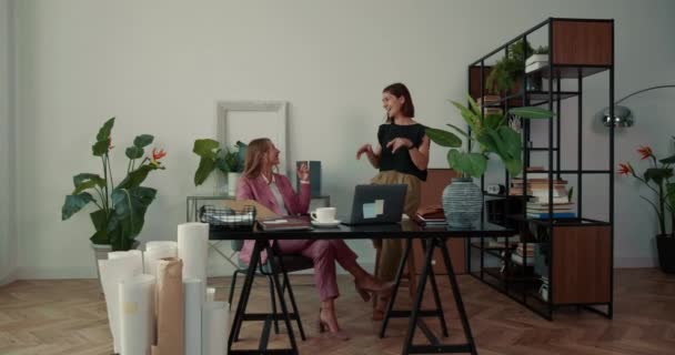 Životní styl portrét dvou krásných profesionálních mladých obchodních žen, které spolupracují u moderního módního kancelářského stolu. — Stock video