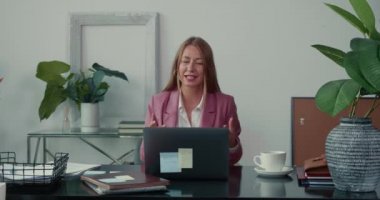 Online çalışıyor. Mutlu başarılı çekici iş kadını ofis masasındaki uzak ortaklarla dizüstü bilgisayar kullanarak konuşuyor..