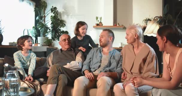 Traditional family values. Happy cheerful mixed age relatives, parents and children talk sitting on couch at light home. — Stock Video