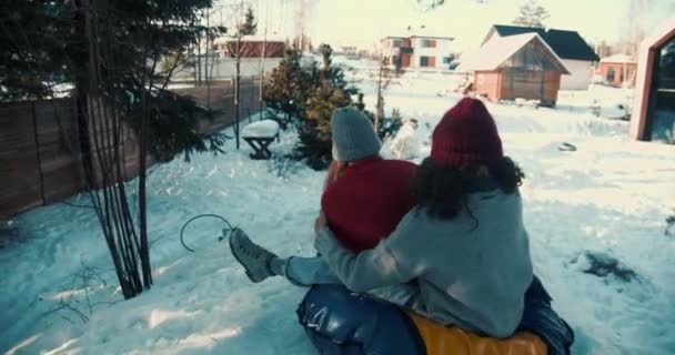 Kamera podąża za dwiema wielonarodowymi szczęśliwymi pięknymi kobietami zjeżdżającymi ze wzgórza do dużego domu ciesząc się zimą zabawy slow motion. — Wideo stockowe