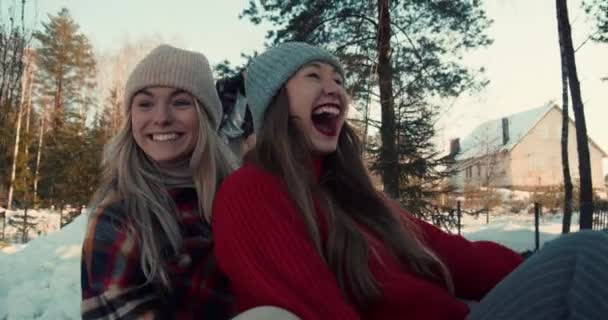 Zimowa zabawa. Dwie piękne podekscytowane szczęśliwe kobiety uśmiech sanki na zboczu lasu śniegu w kierunku aparatu slow motion. — Wideo stockowe
