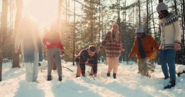 Neşeli, çoklu etnik çeşitlilikte arkadaşların kar gülüşüyle oynayıp güneşli kış orman yürüyüşünün zevkini çıkardığı keyifli bir resim..
