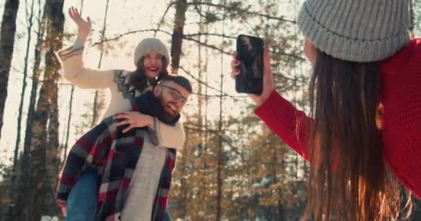 Cheerful friends take photos having fun together at magnificent sunny snowy winter forest, Christmas holiday slow motion — Stock Video