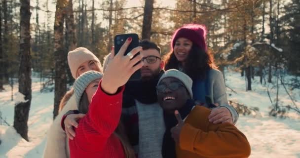 Wiosenne święto. Wesoły szczęśliwy wielonarodowy przyjaciele zrobić selfie zdjęcie razem w słoneczny śnieg zima las slow motion. — Wideo stockowe