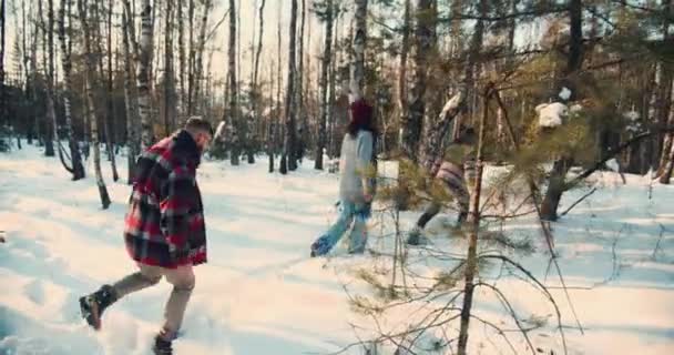 Kamera sleduje skupinu šťastných přátel túru na hluboké zasněžené lesní cestě na slunné Vánoce zimní víkend den zpomalení. — Stock video