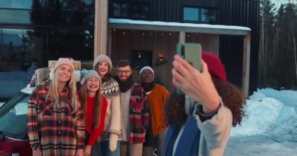 Neşeli, çok ırklı mutlu arkadaşlar, karlı bir Noel gününde, ev terası yakınındaki kırmızı arabada selfie çekiyorlar.. — Stok video