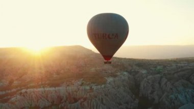 26 Temmuz 2021 CAPPADOCIA TURKEY Epic hava görüntüsü, dağların üzerinden yükselen beyaz sıcak hava balonu.