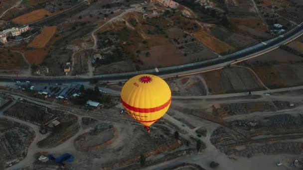 JUL 26, 2021 CAPPADOCIA TURQUÍA Lanzamiento aéreo de gran angular de un gran globo aerostático amarillo volando sobre un paisaje rocoso del desierto. — Vídeos de Stock