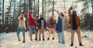 Selfie bağımlılığı. Mutlu çok ırklı insanlar güneşli kış ormanlarında yavaş çekimde bireysel telefon fotoğrafları çekerler..