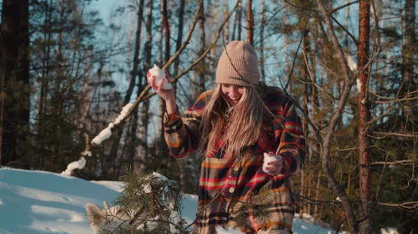 Felice bella eccitato giovane donna bionda tiene, lancia palle di neve ad amici in sorprendente foresta innevata al rallentatore sole. — Foto Stock