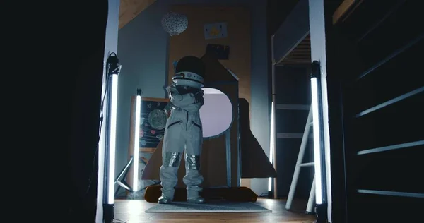 Κινηματογραφικό πλάνο, διαστημάνθρωπο παιδί με στολή αστροναύτη που ποζάρει με σταυρωμένα τα χέρια στο μυστηριώδες σκοτεινό διαστημόπλοιο με καπνό. — Φωτογραφία Αρχείου