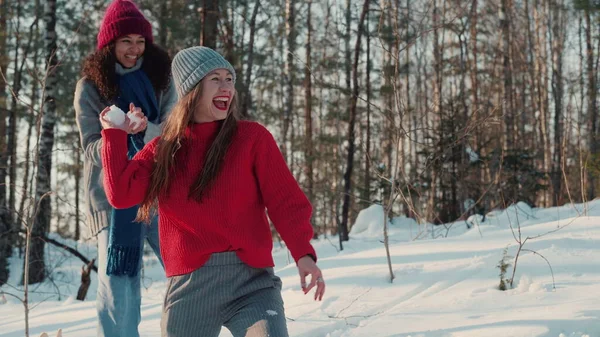 Two happy excited multiethnic young women fight snowballs with friends in beautiful sunny snowy forest slow motion. — Stock Photo, Image