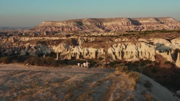 Drone vliegt door gelukkig gezin met kinderen genieten van ongelooflijke berg panorama uitzicht samen zitten op de rand van de klif. — Stockvideo