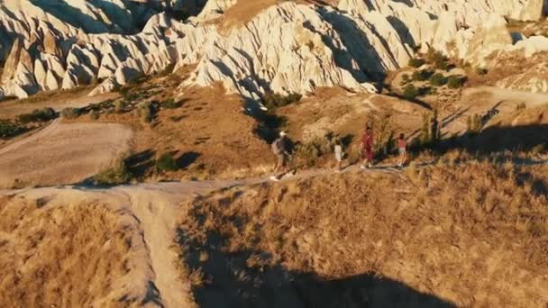 Úžasný letecký pohled, šťastná turistická rodina s dětmi pěší túru podél cesty na vrcholu úsvitu skály v Cappadocia. — Stock video