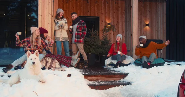 Leuk kerstfeest. Groep gelukkige vrienden met warme dranken dansen in gezellige winter chalet huis slow motion. Stockafbeelding