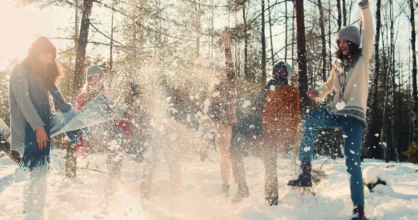 Идиллическая кинематографическая замедленная съемка, веселые веселые многонациональные друзья бросают снег улыбаясь в солнечном зимнем лесу замедленной съемки. — стоковое фото
