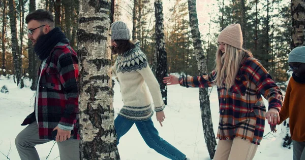 Happy groep van multi-etnische vrienden wandelen langs besneeuwde winterbos pad, genieten van leuke vakanties weekend samen slow motion. Stockfoto