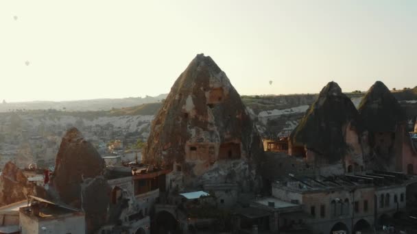 Drone volant par de hautes roches étonnantes avec des portes et des fenêtres à l'intérieur, ville authentique pendant le coucher du soleil en été Cappadoce. — Video