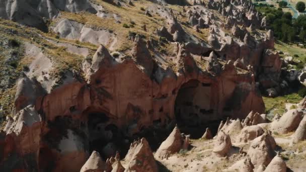 Filmisches Luftpanorama wunderschöner, sonniger uralter Felsen mit Höhlen im Inneren im Sommer in den Bergen Kappadokiens. — Stockvideo