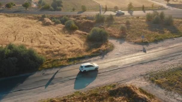 Високий кут відстеження дронів, білий автомобіль рухається по красивій дорозі в сонячному полі під час подорожі, злившись на шосе . — стокове відео