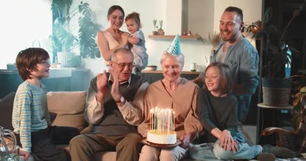 Feliz alegre abuela mayor celebrando cumpleaños con pastel y confeti entre los niños y nietos en casa. — Vídeos de Stock