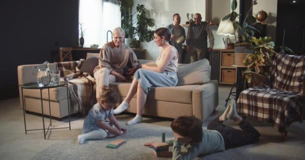Feliz edad mixta Los padres, abuelos e hijos caucásicos comparten un buen tiempo de unión en la sala de estar casera. — Vídeos de Stock