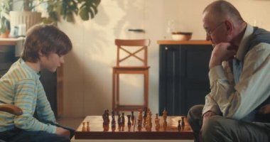 Yan görünüşlü, yakışıklı, genç çocuk düşünen, hafif evde yaşlı büyükbabaya karşı satranç oynayan. Zeka kavramı.