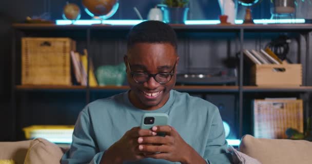 SOCIAL MEDIA CONCEPT Fröhlicher Spaß junger schwarzer Blogger lacht, lächelt SMS an Freunde zu Hause. — Stockvideo
