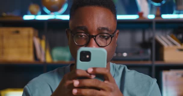 Έκπληξη CONCEPT Κοντινό πλάνο πρόσωπο του ευτυχισμένου μαύρου blogger σε γυαλιά ηλίου κρατώντας smartphone, να εκπλαγείτε και να ενθουσιαστούν. — Αρχείο Βίντεο