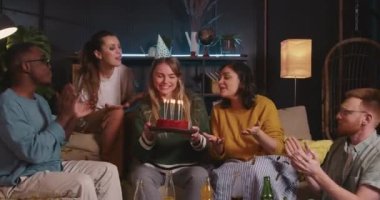 Doğum günü kutlamaları Güzel, mutlu, sarışın kadın çeşitli arkadaşlarla eğlence konfeti evinde dans ederken pastaya üfledi.