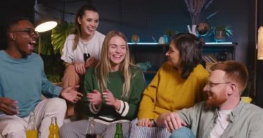 Birliktelik konsepti. Beş heyecanlı, mutlu, çoklu etnik kökenli genç arkadaş gurubu kanepede oturmuş neşeyle gülüyor..