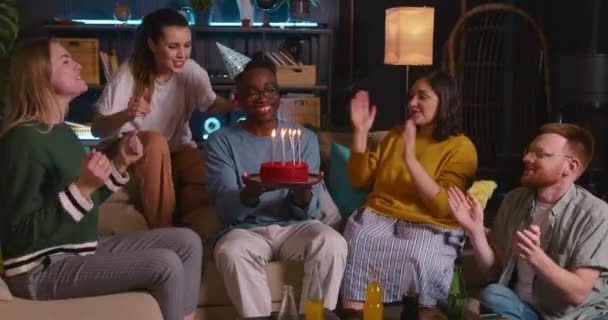 Alegre amigos multiétnicos parabenizar divertido feliz jovem de 20 anos afro-americano homem celebrando aniversário soprando no bolo. — Vídeo de Stock