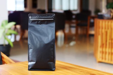 Kafe masasının üzerinde duran kahve poşeti büyüklüğündeki fotoğraf. Yapıştırma etiketleri, kahve varyantı ambalaj etiketleri veya benzeri şeyler için uygun.