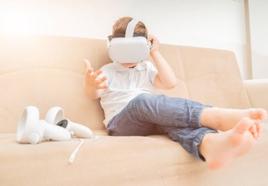 Sanal gerçeklik gözlüğü takan genç bir çocuk, beyaz çocuk VR kulaklık kullanıyor, video oyunları oynuyor.