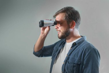 Genç bir adam dürbün resmine bakar.