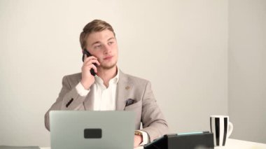 Ofisteki genç yakışıklı adamın akıllı telefondan konuşma görüntüsü.