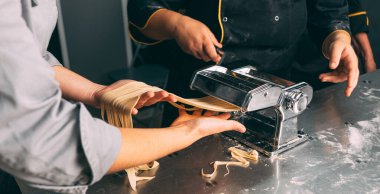 Profesyonel bir mutfakta fotoğraf makarna hazırlama işlemini kapat. İki kadın özel bir makine kullanıyor..