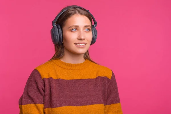 Giovane donna indossa un paio di cuffie su sfondo rosa. — Foto Stock