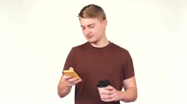 Akıllı telefon kullanan ve elinde kahve tutan genç bir adamın görüntüsü.