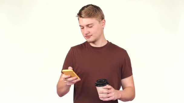 Nagranie młodego przystojniaka używającego smartfona i trzymającego filiżankę kawy na wynos — Wideo stockowe