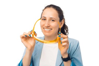 Genç, gülümseyen bir kadın beyaz arka planda turuncu bir gözlük takıyor..