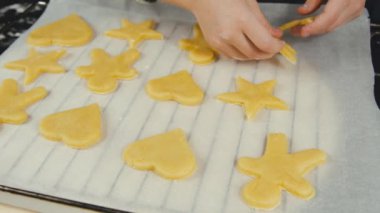 Yakın çekimde zencefilli kurabiye yapan ve pişirmeye hazırlanan bir kız görülüyor.