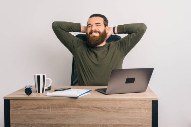 Neşeli genç sakallı adam ofiste önemli bir anlaşma yaptıktan sonra dinleniyor..