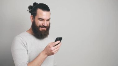 Gri arkaplan üzerinde akıllı telefon kullanan mutlu adamın görüntüsü
