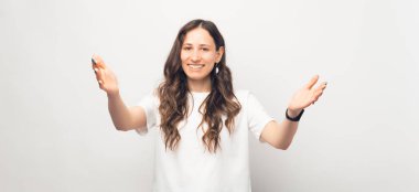 Neşeli genç bayan beyaz arka planda hoş geldin jestleri yapıyor.